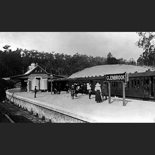 A century old photograph of Glenbrook Railway Station, a wooden passenger train at platform with many well-dressed passengers embarking and disembarking.