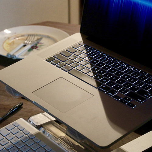 image of a laptop keyboard, and next to it a saucer with a knife and fork, and leftover crumbs on it